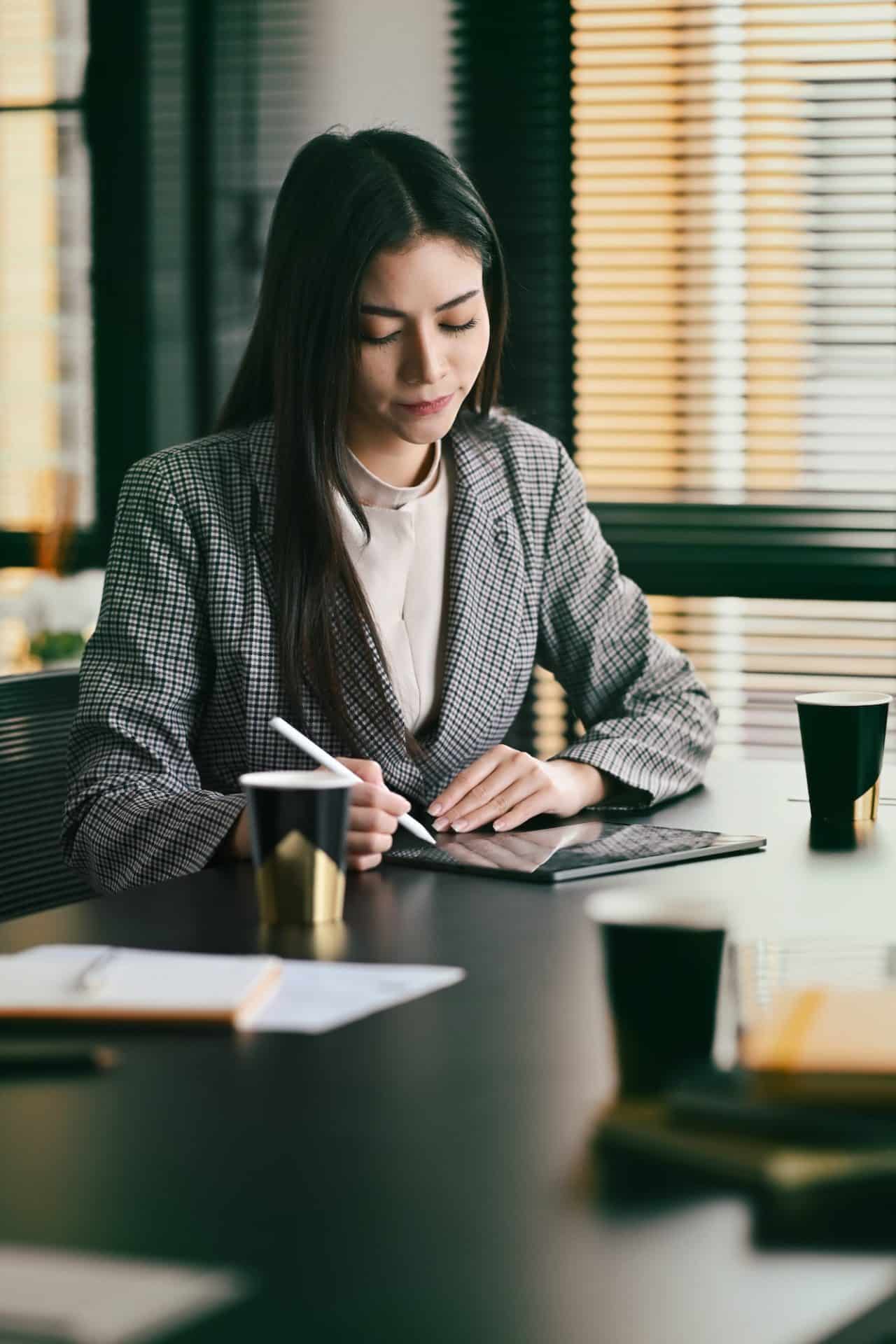 concentrated female manager sitting at her workplace and writing important information on notebook